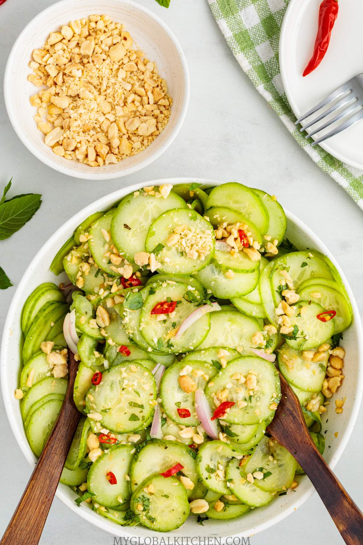 Overhead shot of a bowl of cucumber salad with a bowl of crushed peanuts next to it