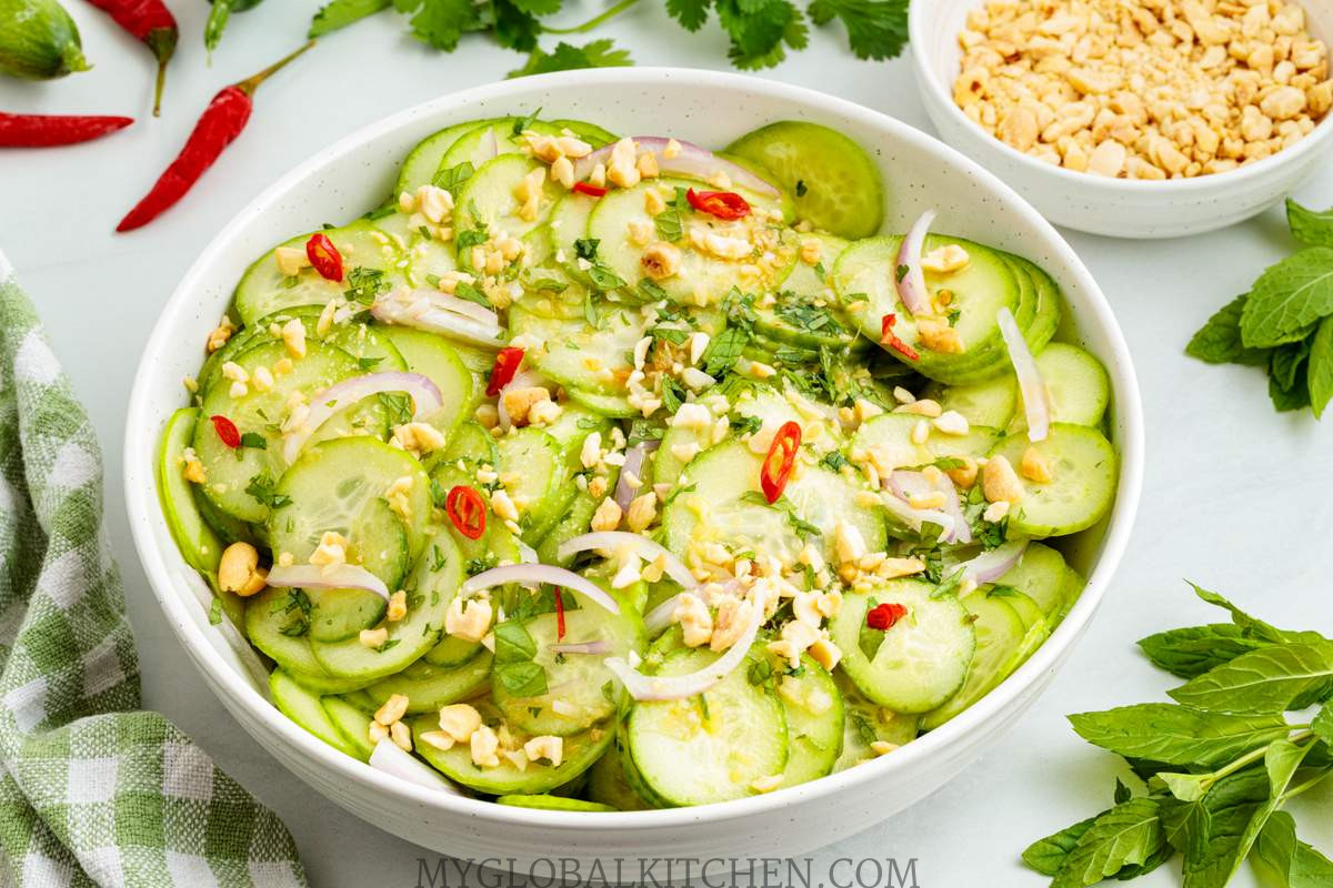 Thai Cucumber Salad with crushed peanuts and chopped chilies on top in a white bowl