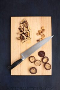 Mushrooms being sliced on a wooden board