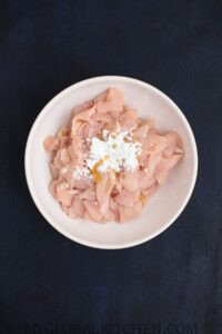 Chicken slices with cornstarch in a white bowl
